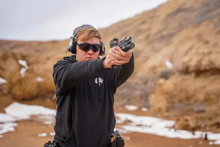 Shooter aiming a pistol at an outdoor range