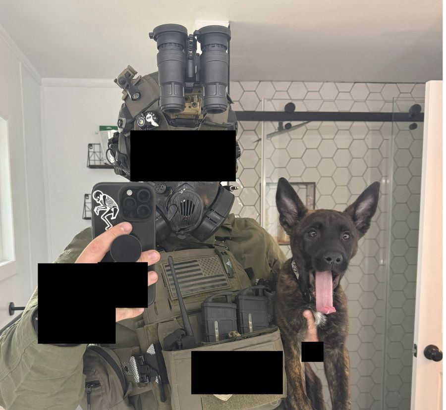 Kyle in full gear holding Fen, a Belgian Malinois and Dutch Shepherd mix, with identifying details blacked out
