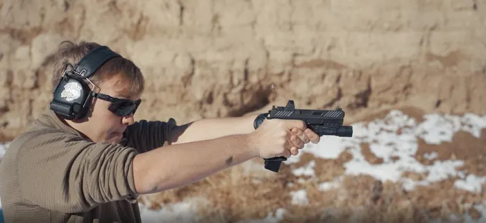 Student shooting a pistol at an outdoor range